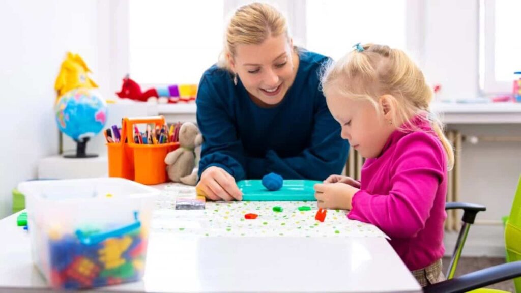 A Registered Behavior Technician working one-on-one with a young child during an ABA therapy session, using colorful educational materials in a bright, engaging environment.